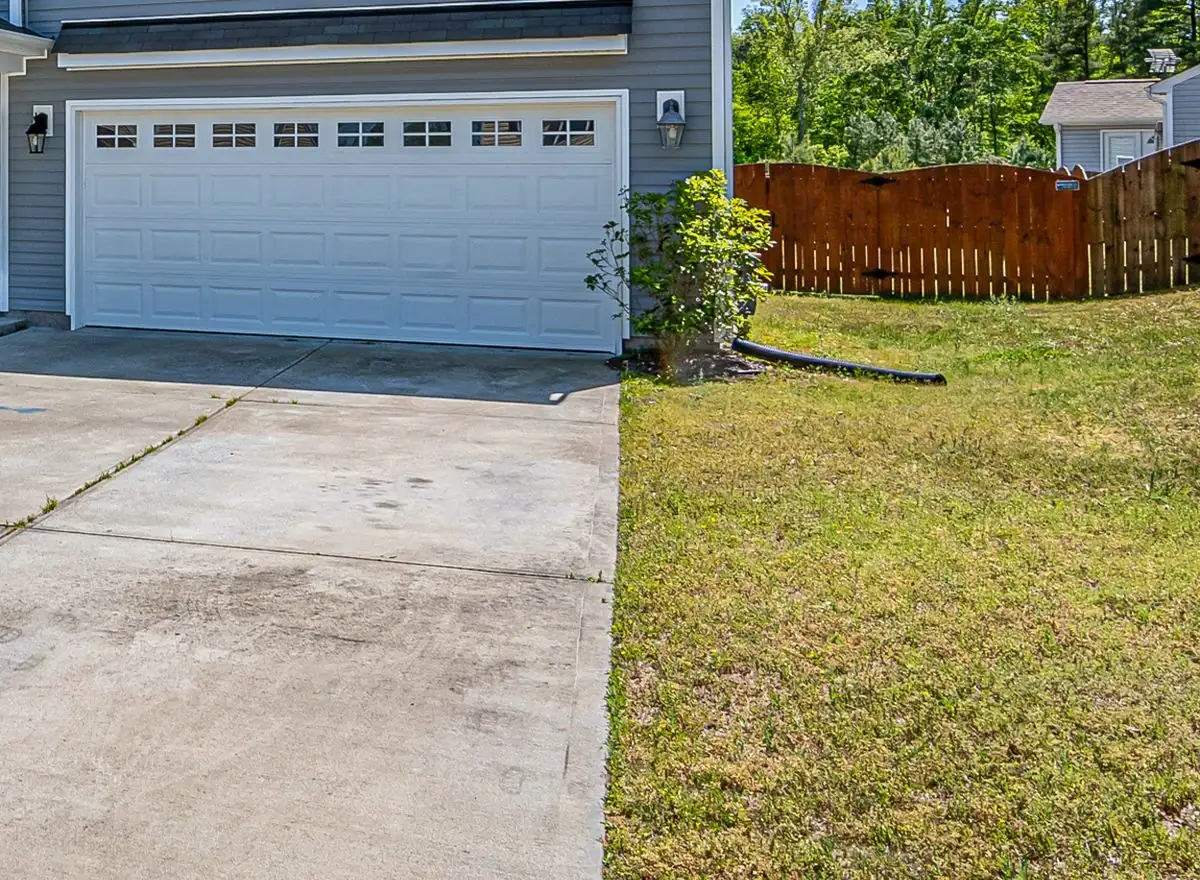 Broom-finished concrete driveway with sawn control joints leading to a two-car garage