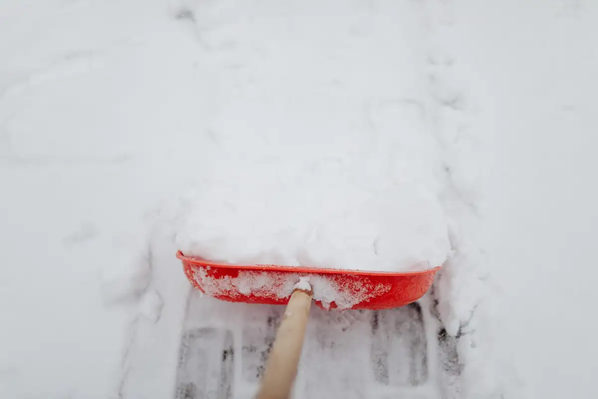 Snow shovel clearing a strip across a concrete slab