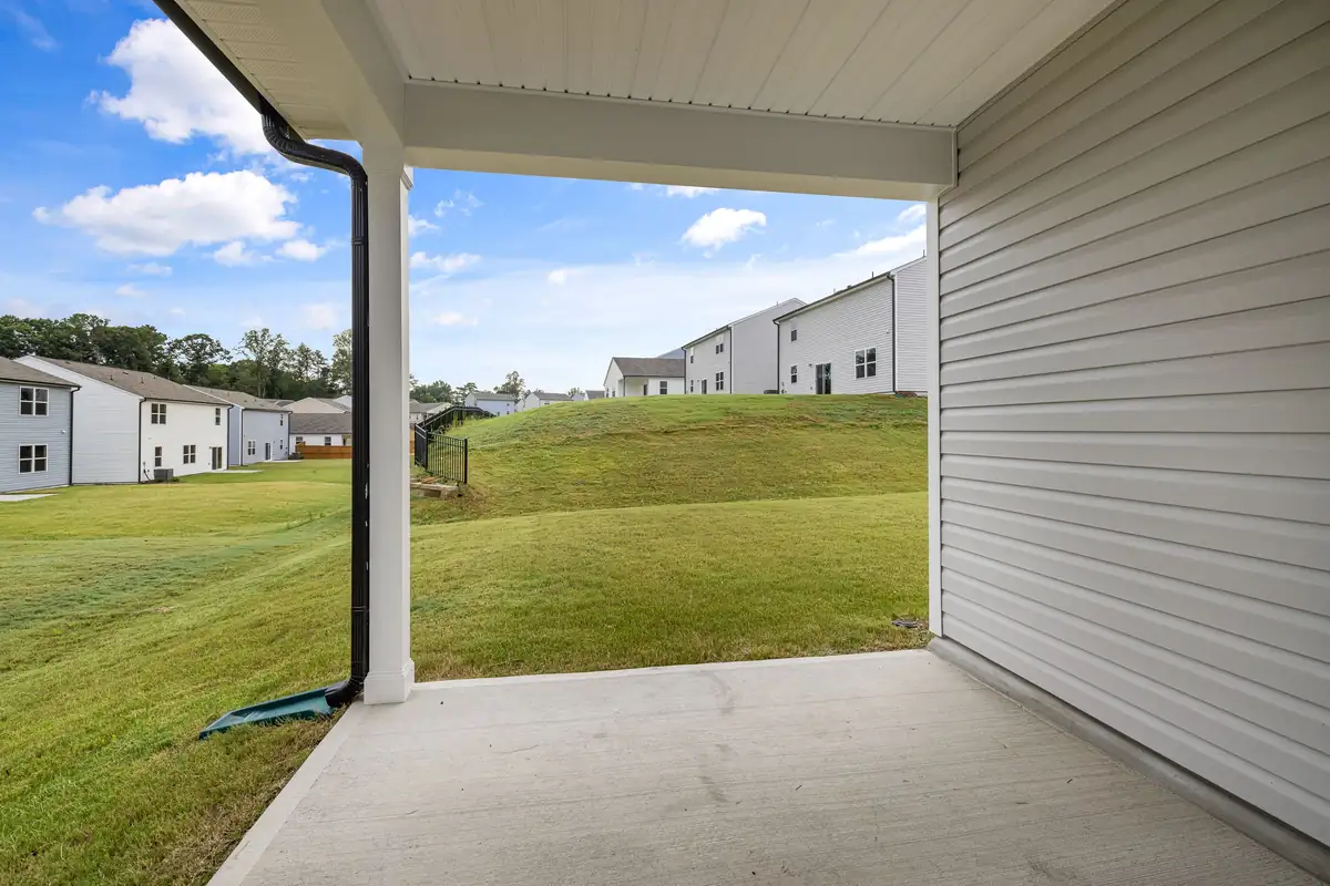 Plain broom-finished concrete patio under a covered porch, looking out over a back lawn
