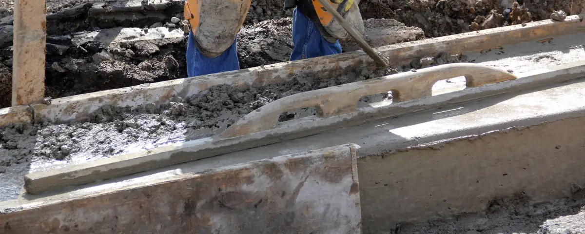 Finisher in knee pads working fresh concrete inside wood forms with a hand float