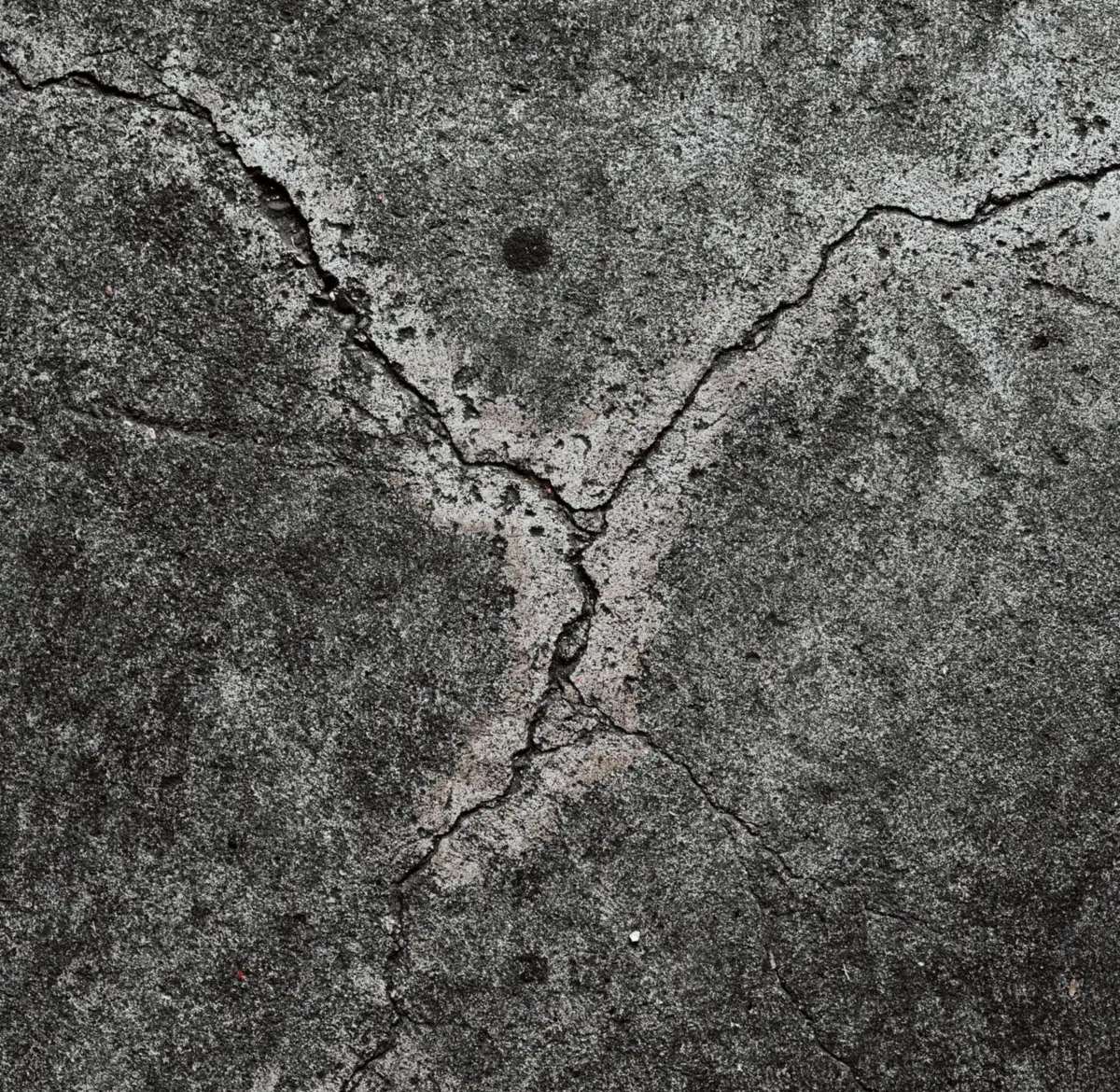 a weathered concrete surface with branching map cracks.
