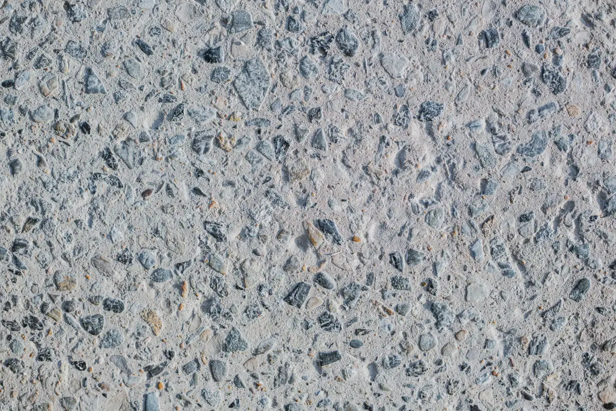 Exposed aggregate concrete surface with rounded gray and blue stones set in cement paste